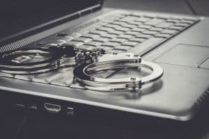 handcuffs on laptop cyber crime concept