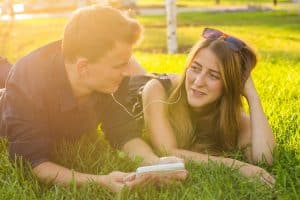 Young couple lie on grass listening to music