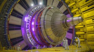 Illustration of a massive superconducting magnet being assembled for the ITER fusion reactor project.